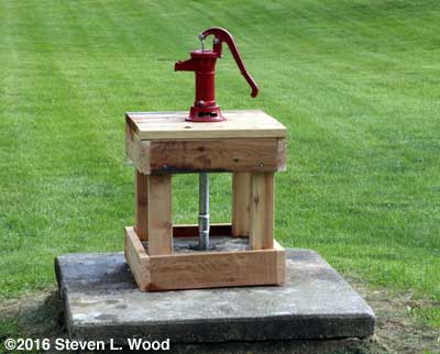 Pitcher pump on stand over shallow well