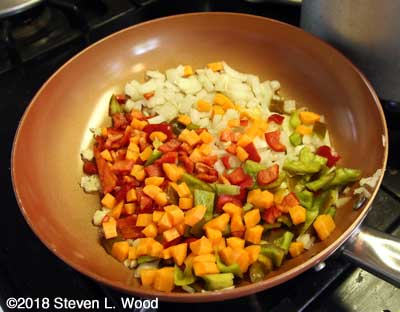Onion, garlic, carrots, and peppers sautéing in pan