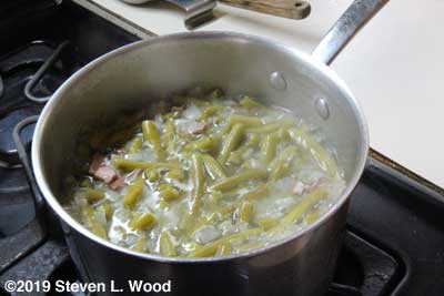 Green beans in the pot with bacon, ham, and onions for seasoning